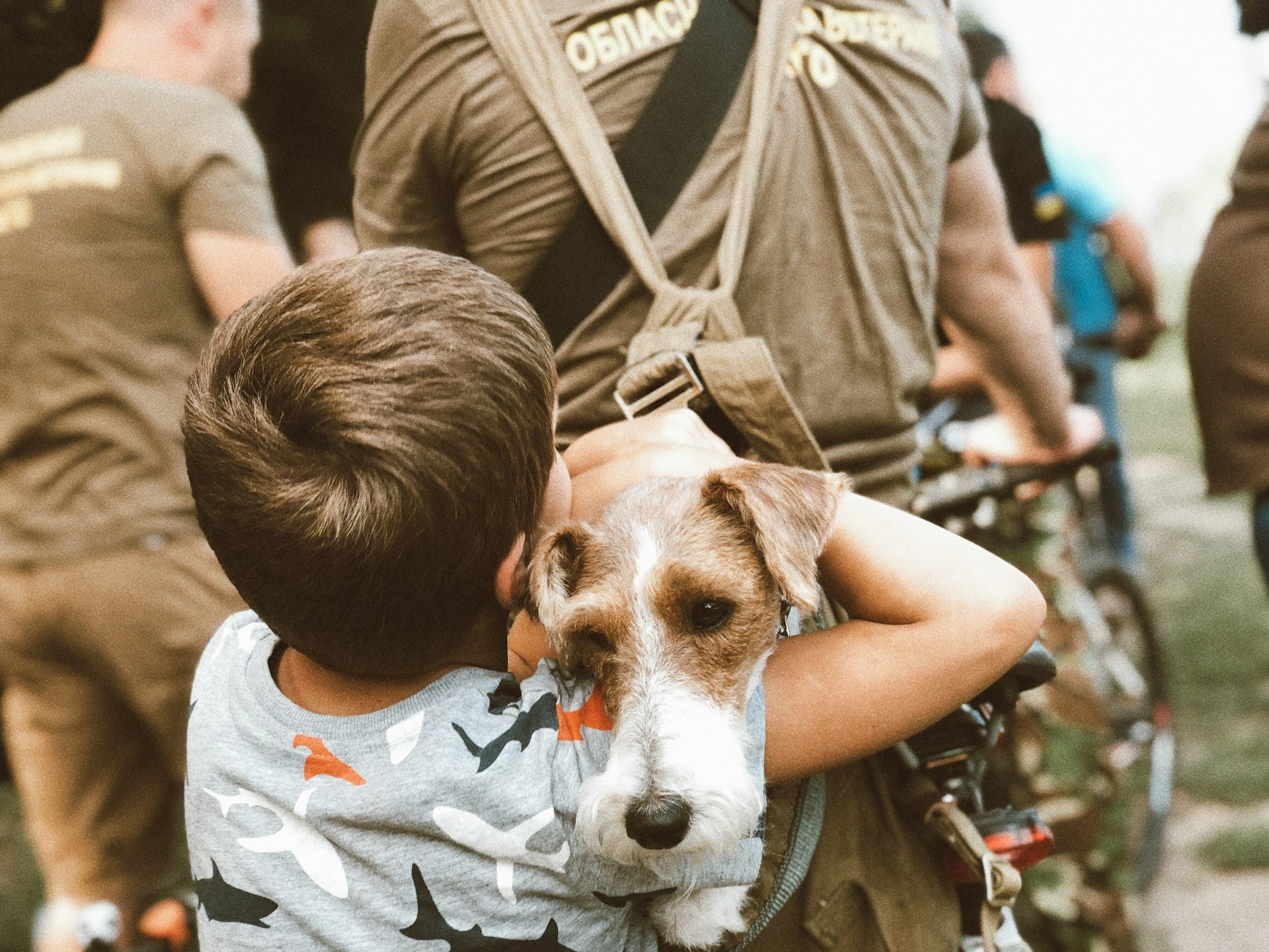 The dog's face is visible as a child's arm is wrapped around it, being carried in a bagpack.